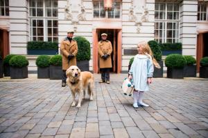 una niña y un perro delante de un edificio en Rosewood London en Londres