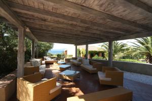 un patio al aire libre con sofás, mesas y sillas en Residence Baia Salinedda, en San Teodoro