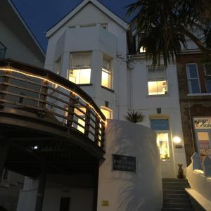 uma casa branca com um alpendre e um edifício em The White House Hotel em Newquay