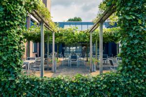 un patio con mesas, sillas y plantas en Mercure Hotel Zwolle en Zwolle