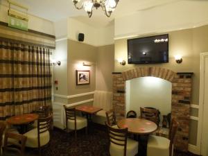 een restaurant met tafels en stoelen en een televisie aan de muur bij Eskdale Lodge in Sale