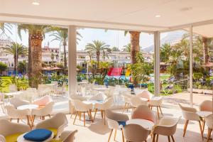 een restaurant met witte stoelen en tafels en palmbomen bij Port Denia in Denia