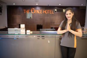 Una mujer parada frente a un mostrador con las manos al frente en The Space Hotel Chiang Rai, en Chiang Rai