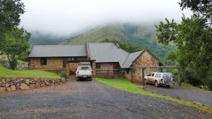 une maison avec deux camions garés devant elle dans l'établissement Verlorenkloof, à Dullstroom