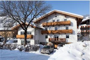 un edificio con un coche aparcado en la nieve en Pension Rosenhof en Brixen im Thale