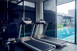 - une salle de sport avec deux tapis de course à côté d'une piscine dans l'établissement M Roof Hotel & Residences, à Ipoh