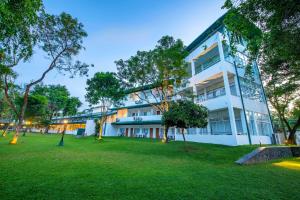 un gran edificio blanco con árboles delante de él en Hotel Sudu Araliya en Polonnaruwa