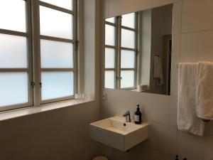 baño blanco con lavabo y 2 ventanas en Hotel VANDret en Løkken