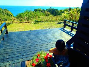 uma mulher sentada num alpendre com flores em Yakushima Cottage Morino Fairy em Yakushima