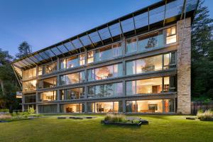 un gran edificio de cristal con un patio delante en Calfuco Wine Hotel & Spa en Villa La Angostura