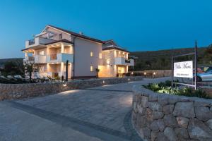 una casa grande con una pared de piedra y un camino de entrada en B&B Villa Maris Punat, en Punat