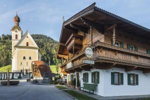 un edificio con un reloj al lado de una iglesia en Pension Sunnberg en Going