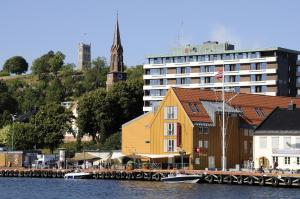 un gran edificio amarillo junto a un edificio junto al agua en Thon Hotel Tønsberg Brygge en Tønsberg