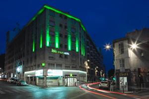 - un bâtiment vert dans une rue de la ville la nuit dans l'établissement ibis Styles Marseille Centre Prado Place Castellane, à Marseille