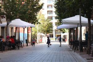 uma criança andando por uma rua com mesas e guarda-sóis em LarDviura em Logroño