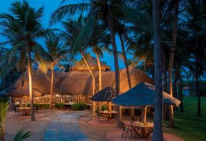 un complexe avec des tables et des palmiers la nuit dans l'établissement Radisson Blu Resort Temple Bay Mamallapuram, à Mahabalipuram