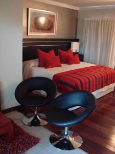 a bedroom with a bed and two black chairs at Zoom Apartments Hotel in Cordoba