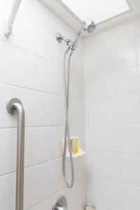 a shower head in a white tiled bathroom at Ilima Hotel in Honolulu