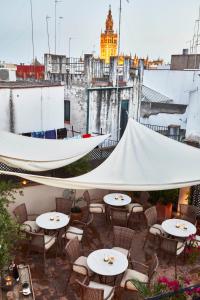 un patio con mesas y sillas y una tienda blanca en Hotel Boutique Corral del Rey, en Sevilla