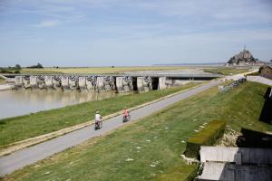 duas pessoas a andar de bicicleta numa estrada ao lado de um rio em Le Relais Du Roy em Monte de Saint Michel