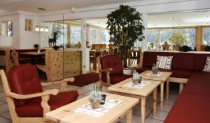 un restaurante con mesas de madera y sillas rojas en Hotel Garni Panorama, en Scuol