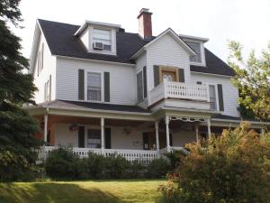 een wit huis met een veranda en een balkon bij Au Manoir de la rue Merry in Magog-Orford