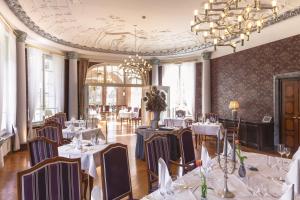 uma sala de jantar com mesas e cadeiras e um lustre em Das Wolfsbrunn em Hartenstein