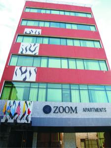 a tall red building with a sign on it at Zoom Apartments Hotel in Cordoba