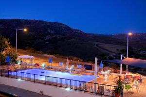 ein Pool mit Stühlen und Sonnenschirmen in der Nacht in der Unterkunft Peyia Pearl in Peyia