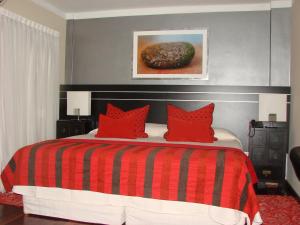 a bedroom with a red and black bed with red pillows at Zoom Apartments Hotel in Cordoba