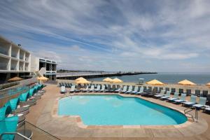 una piscina con sillas y sombrillas y el océano en Dream Inn Santa Cruz en Santa Cruz