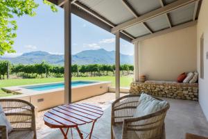 eine Terrasse mit einem Tisch und Stühlen sowie einem Pool in der Unterkunft La Chataigne Wines & Guest Cottages in Franschhoek