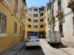 un coche blanco aparcado en un callejón frente a un edificio amarillo en Hotel Brasilia en Santiago