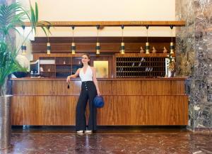 a woman standing in front of a wooden bar at Parkhotel Pörtschach - Das Hotelresort mit Insellage am Wörthersee in Pörtschach am Wörthersee