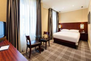 a hotel room with a bed and a desk and a television at Radisson Blu Hotel, London South Kensington - formerly Vanderbilt in London