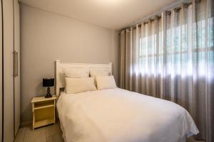 a bedroom with a white bed and a window at Cozumel 320 in Umdloti