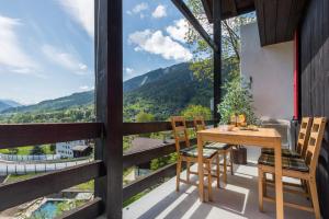 una mesa de madera y sillas en un balcón con vistas en Chalet Ravenstein, en Fiesch