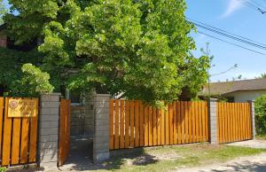 una recinzione di legno con un albero di fronte a una casa di Napraforgó Vendégház a Gárdony