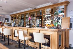 un bar con taburetes blancos en una habitación en The Clarendon Royal Hotel en Gravesend