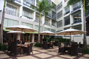 un patio extérieur avec des tables, des chaises et des parasols dans l'établissement The Avenue Plaza Hotel, à Naga