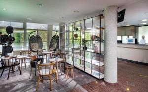 un restaurante con mesas, sillas y estanterías de cristal en Seminaris Hotel Potsdam Griebnitzsee, en Potsdam