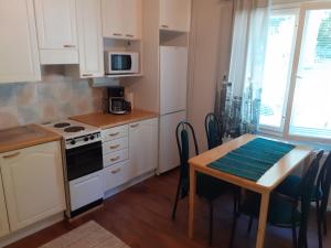 a kitchen with white cabinets and a table with a stove at huoneisto 2 in Savonlinna