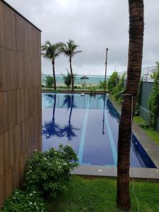 uma piscina com uma palmeira ao lado de um edifício em Apartamento com vista pro mar - Beach Way em Aquiraz