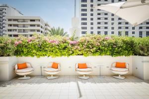 eine Reihe von Stühlen mit orangefarbenen Kissen auf einer Terrasse in der Unterkunft Berkeley Shore Hotel in Miami Beach