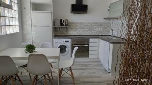 une cuisine avec une table et des chaises blanches ainsi qu'une cuisine avec un lave-linge dans l'établissement Apartamento La Luna, à Lumpiaque