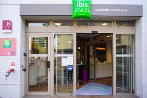 une entrée à un bâtiment avec un panneau sur celui-ci dans l'établissement ibis Styles Marseille Centre Prado Place Castellane, à Marseille