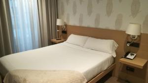 1 dormitorio con 1 cama blanca y 2 mesas con lámparas en Hotel Atalaia en Santiago de Compostela