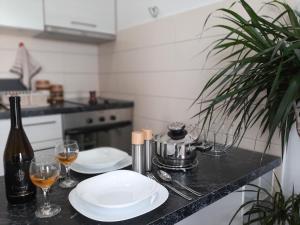 - un comptoir de cuisine avec 2 assiettes et des verres de vin dans l'établissement Beki Apartment, à Bar