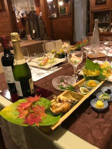 - une table avec une bouteille de vin et des assiettes de nourriture dans l'établissement Yamagata Zao Pension Aplon Stage, à Kaminoyama