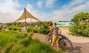 um rapaz ao lado de uma bicicleta em Camping Veld & Duin em Bredene